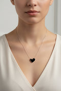 Black heart-shaped pendant on a silver chain against a white background