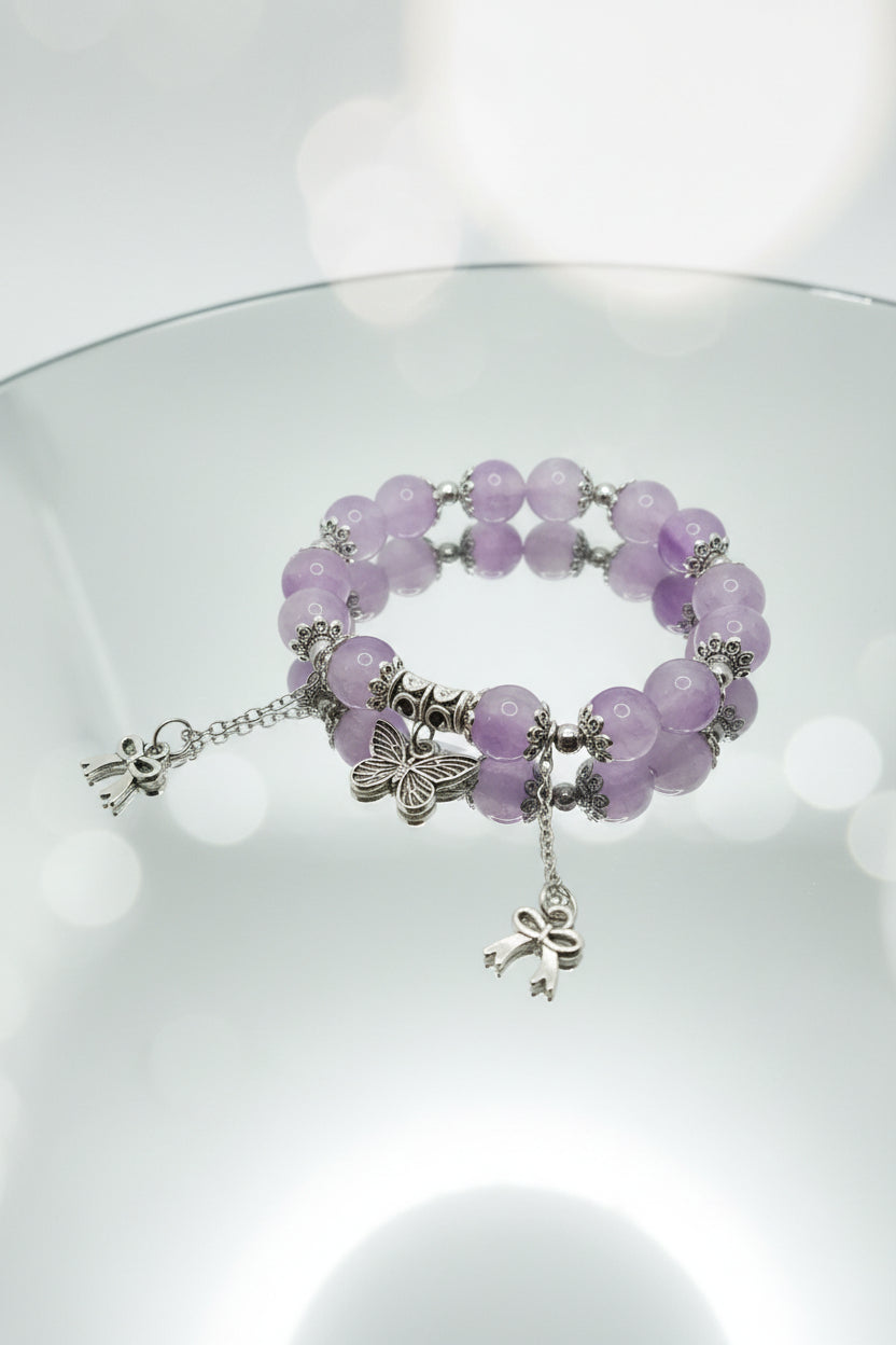 Purple beaded bracelet with butterfly charms on a white background